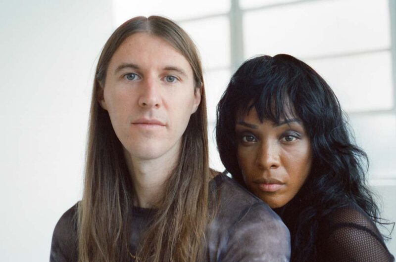 Dawn Richard stands behind Spencer Zahn. They are both looking towards the camera.