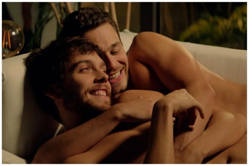 Two individuals embracing and smiling on a couch, with a warmly lit background suggesting an intimate and cozy setting.