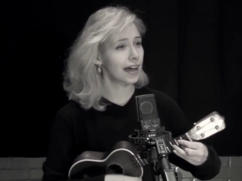 Screen grab from live performance, in black and silver. Nellie McKay sings and plays the Ukulele