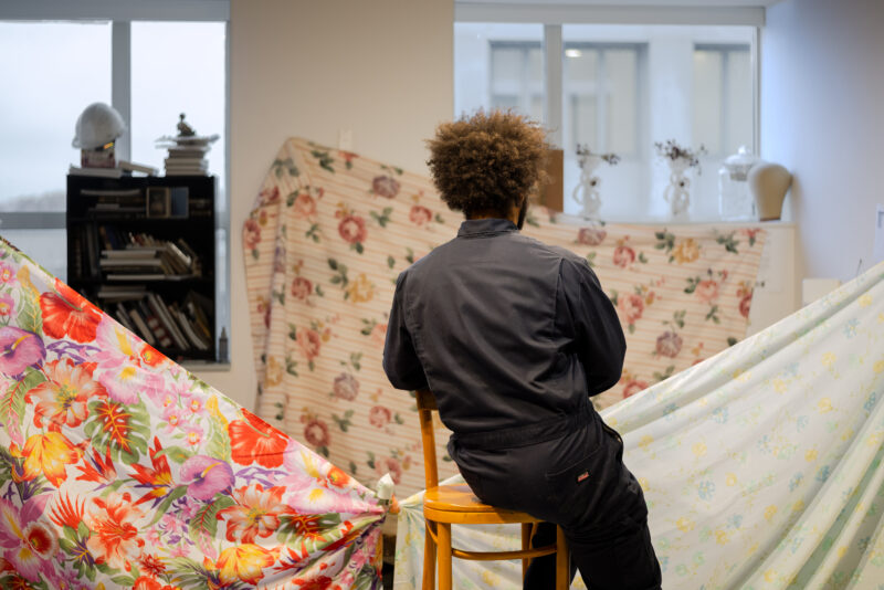 A photograph of Frank Marlin from the back, looking at floral sheets